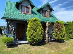 ein Haus mit einem grünen Dach und zwei Büschen in der Unterkunft Domki Maharówka Ostrowo in Ostrowo