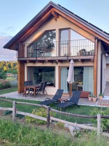 a house with a deck with chairs and an umbrella at BEe in foREST in Pivka