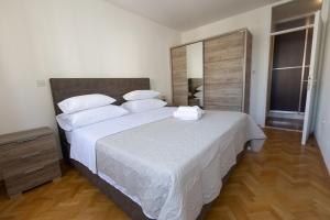 a bedroom with a large bed with white sheets and pillows at Apartment Srecko in Omiš