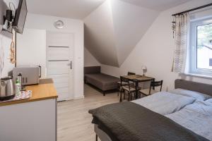 a bedroom with a bed and a kitchen with a table at Dom Gościnny Latarenka in Niechorze