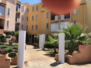 una fila de edificios con palmeras en un patio en Gruissan (Aude) Appartement calme, vue sur port de plaisance -Clim, Empl.Parking, en Gruissan