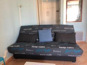 un sofá negro sentado en una habitación con palabras en él en Gruissan (Aude) Appartement calme, vue sur port de plaisance -Clim, Empl.Parking, en Gruissan