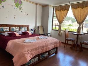 a bedroom with a bed with two towels on it at Hostal Arauco in Otavalo