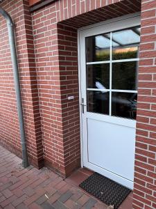 a white door on the side of a brick building at Mein Nordlicht in Südbrookmerland