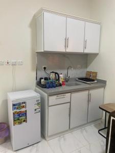 kuchnia z białymi szafkami, zlewem i lodówką w obiekcie Wind alula w mieście Al-Ula