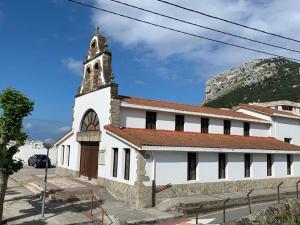 una iglesia blanca con una torre con una montaña en el fondo en Preciosa casa con jardín en Oriñon, en Oriñón