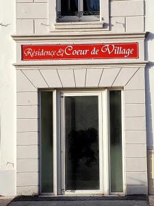 Résidence Cœur de Village في جوسيير: مبنى أبيض مع علامة حمراء على باب