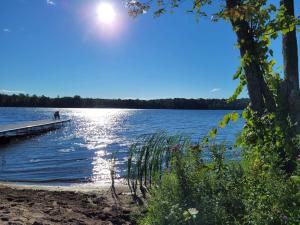 ein Dock auf einem See mit Sonne auf dem Wasser in der Unterkunft Inspire Beach 3 Total Cabins - Beachfront and Waterfront -Hot Tubs & Sauna in Kawartha Lakes