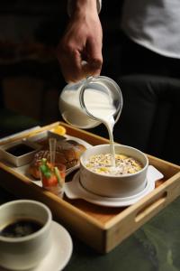 a person is pouring milk into a bowl of food at Hotel Opera in Prishtinë