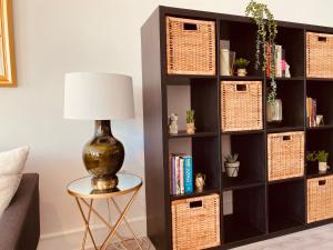 a black book shelf with baskets and a lamp at Spacious 2 Bedroom City pad in Old Street London in London