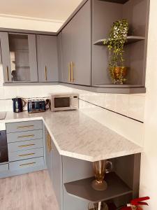 a kitchen with white cabinets and a marble counter top at Spacious 2 Bedroom City pad in Old Street London in London