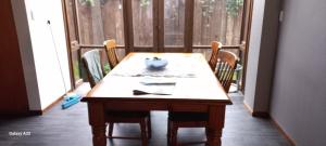 una mesa de madera en una habitación con sillas y una ventana en City Bungalow en Tauranga