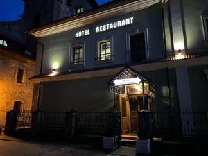 a hotel restaurant with the front door lit up at night at U Dominicana in Kamianets-Podilskyi