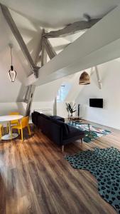 a living room with a black couch and a table at RhizHome - Coeur de ville, appartement spacieux in Auxerre