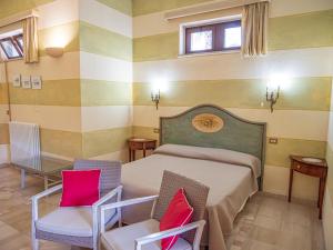 - une chambre avec un lit et deux chaises dans l'établissement Agriturismo Masseria Alcorico, à Gagliano del Capo