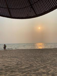 a couple walking on the beach at sunset at Grand Florida Holiday Home in Na Jomtien