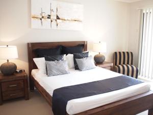 a bedroom with a large bed and a chair at Edge Apartments Cairns in Cairns