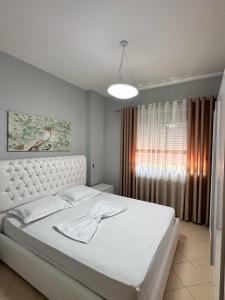 um quarto com uma cama branca e uma janela em Solei Apartments em Saranda