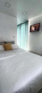 a bedroom with a large white bed with a tv on the wall at Tiny Village Mamaia Nord - House 2 in Mamaia Nord