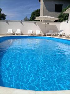 uma grande piscina azul com cadeiras e um guarda-sol em Tiny Village Mamaia Nord - House 4 em Mamaia Nord – Năvodari
