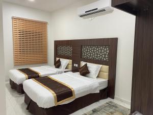 une chambre avec deux lits et une télévision au mur dans l'établissement Wind alula, à Al-Ula