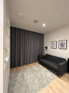 Sala de estar con sofá negro y alfombra gris en London LuXXe Suites & Apartments - London Heathrow Airport, Terminal 1 2 3 4 5, en New Bedfont