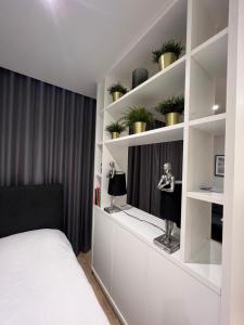 - une chambre avec un lit et des étagères avec des plantes dans l'établissement London LuXXe Suites & Apartments - London Heathrow Airport, Terminal 1 2 3 4 5, à New Bedfont