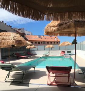 einen Pool mit Stühlen und Sonnenschirmen in der Unterkunft Pisos viajer@s in O Grove