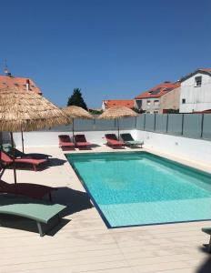 einen Pool mit Stühlen und Sonnenschirmen in einem Resort in der Unterkunft Pisos viajer@s in O Grove