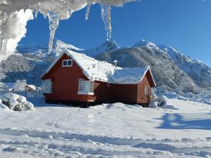 una casa roja con nieve en el techo en la nieve en Cabana Vista Nevada, en Nevados de Chillán