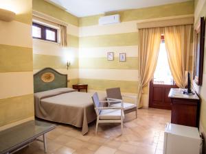 sypialnia z łóżkiem, krzesłem i telewizorem w obiekcie Agriturismo Masseria Alcorico w mieście Gagliano del Capo