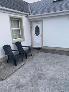 dos sillas negras sentadas frente a una casa en JMD Lodge - Self Catering Property in the heart of The Burren between Ballyvaughan, Lisdoonvarna, Doolin and Kilfenora in County Clare Ireland en Ballyvaughan