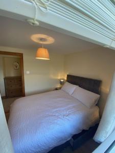 a bedroom with a white bed with a light at JMD Lodge - Self Catering Property in the heart of The Burren between Ballyvaughan, Lisdoonvarna, Doolin and Kilfenora in County Clare Ireland in Ballyvaughan