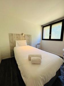 sypialnia z dużym białym łóżkiem z 2 ręcznikami w obiekcie Hôtel Le Forestia w mieście Pannes