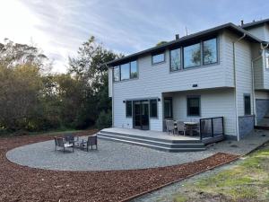 a large white house with a patio with tables and chairs at Fabulous Beach Get Away - Brand New Beach House in Half Moon Bay