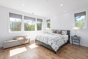 a white bedroom with a bed and a chair at Fabulous Beach Get Away - Brand New Beach House in Half Moon Bay