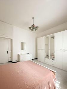 a white bedroom with a pink bed and white cabinets at Tra Cielo e Mare in Follonica