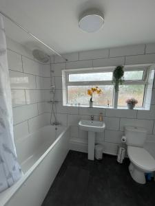 a bathroom with a tub and a toilet and a sink at Large Stylish 2 Bedroom Apartment Stevenage Sleep 6 in Stevenage