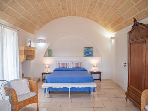 - une chambre avec un lit bleu et une chaise dans l'établissement Agriturismo Masseria Alcorico, à Gagliano del Capo