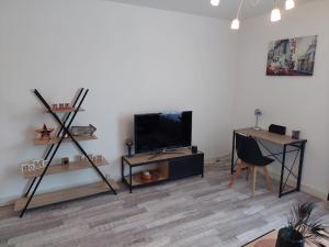 a living room with a flat screen tv and a desk at Appartement équipé proche aéroport et gare in Beauvais