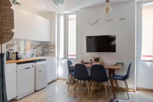a kitchen with white cabinets and a table and chairs at Appartement le Quai du Port Cassis parking clim in Cassis