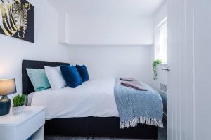 ein weißes Schlafzimmer mit einem Bett mit blauen Kissen in der Unterkunft Beautiful apartment DOS in Litherland