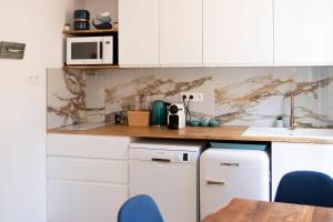 a kitchen with white cabinets and a wooden counter top at Appartement le Quai du Port Cassis parking clim in Cassis