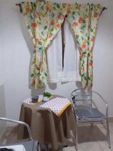 una mesa y una silla junto a una ventana con cortinas en Departamento Celsa en Salta