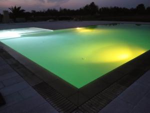 uma piscina com iluminação verde e amarela em Masseria Cricelli em Lizzanello