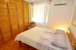 een slaapkamer met een bed met witte lakens en een raam bij Apartment OAZA in Kotor