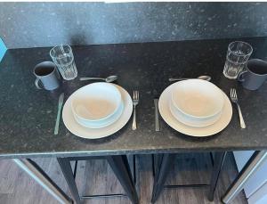 uma mesa com dois pratos, garfos e copos em Spacious 2bedroom property by Star Suites em Elswick