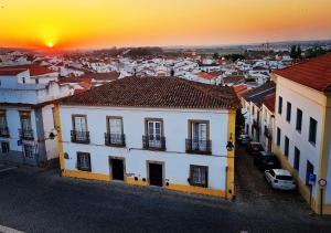 Blick auf eine Stadt mit Gebäuden und den Sonnenuntergang in der Unterkunft Casa de Diana in Évora