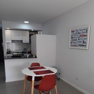 uma cozinha com uma mesa branca e 2 cadeiras vermelhas em Loft Dorrego Rio em Rosário