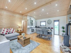 a living room with a couch and a kitchen at Alpaca Lodge in Barkston